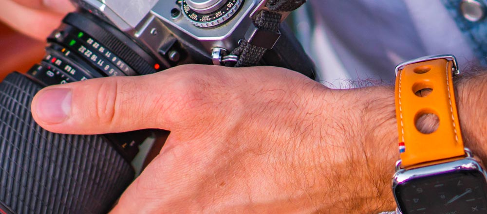 bracelet rallye Apple Watch sur un poignet masculin tenant un appareil photo